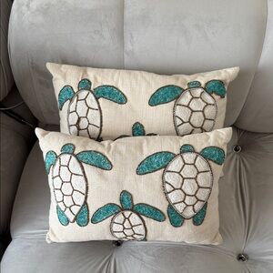 Blue and gold beaded coastal life pillows on tan linen.